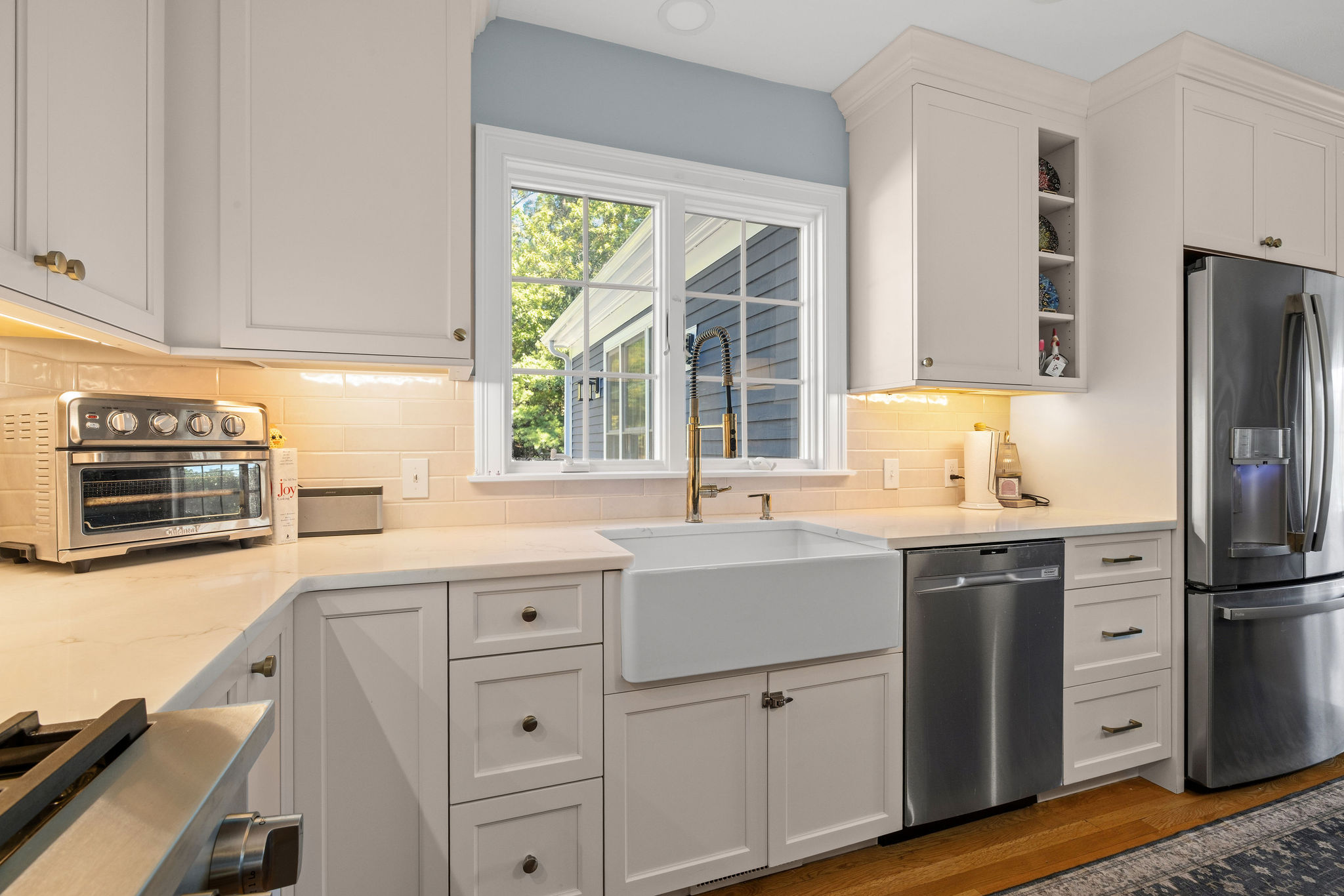 Farmhouse sink under a window with white cabinetry and quartz counters in a Hanover kitchen
