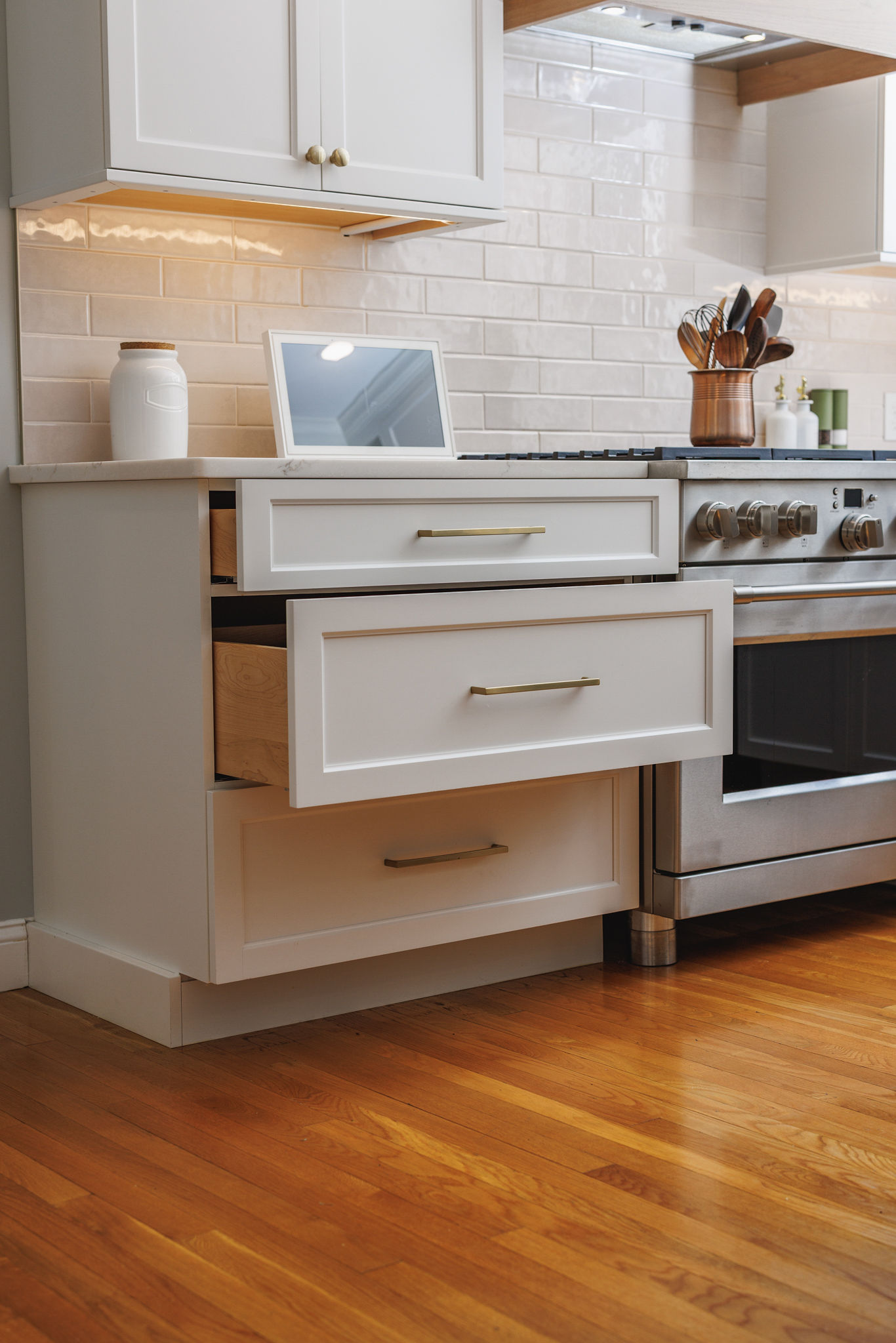 White cabinetry drawers with brass pulls beside a stainless range in a Hanover kitchen remodel.