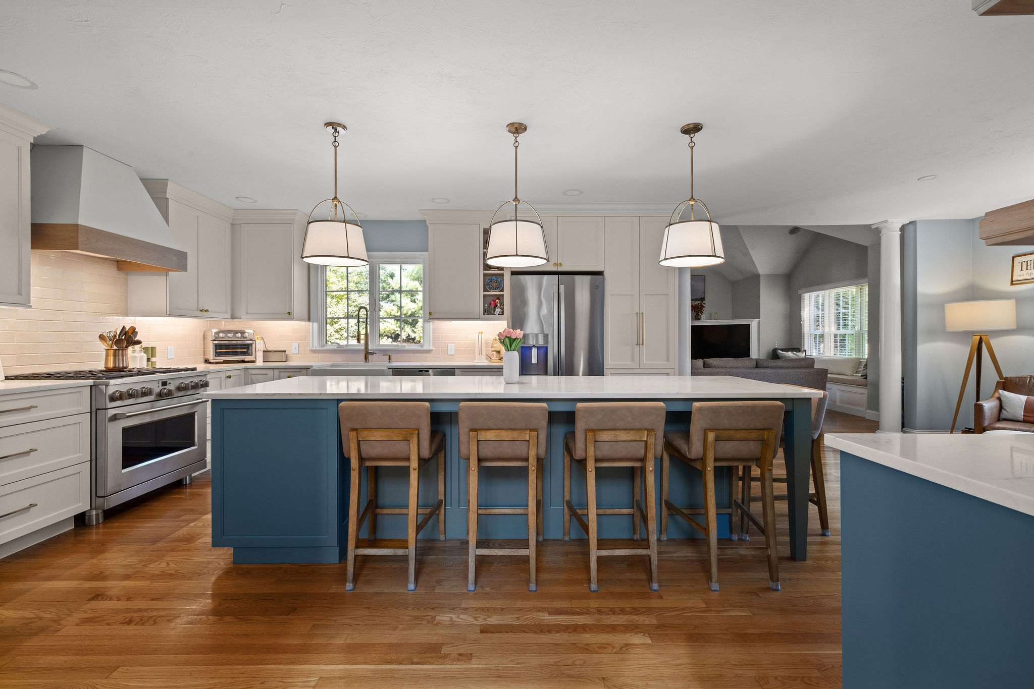 Seaglass island with counter stools, brass pendants, and a stainless range in a Hanover kitchen remodel
