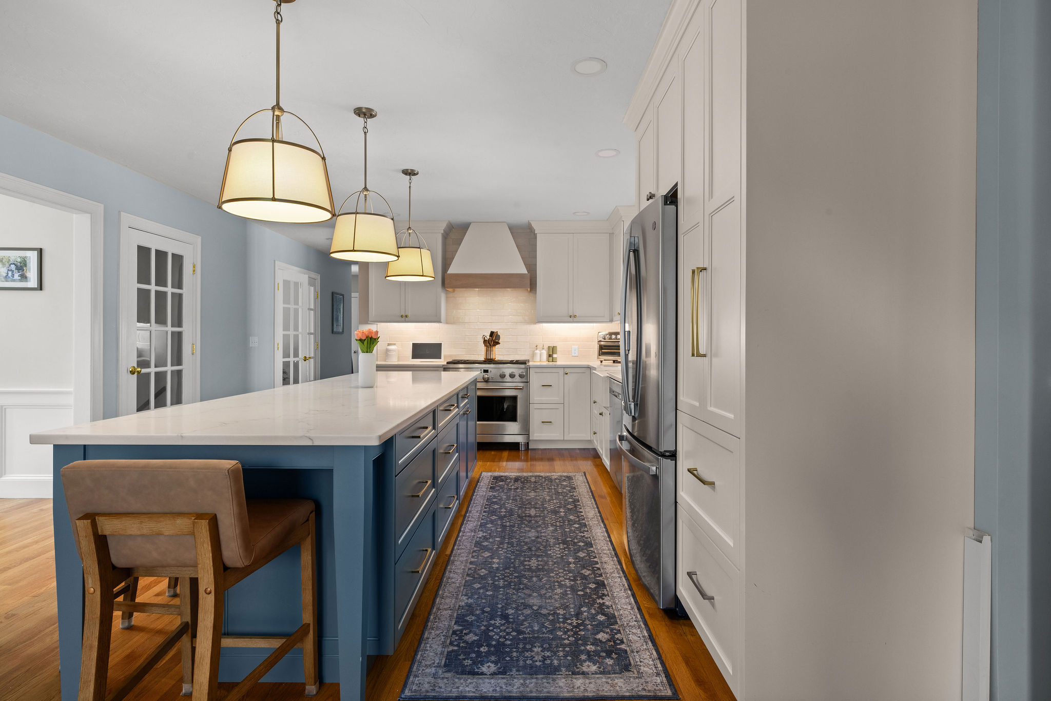 Hanover kitchen with a Seaglass island, brass pendants, and quartz counters open to the living area