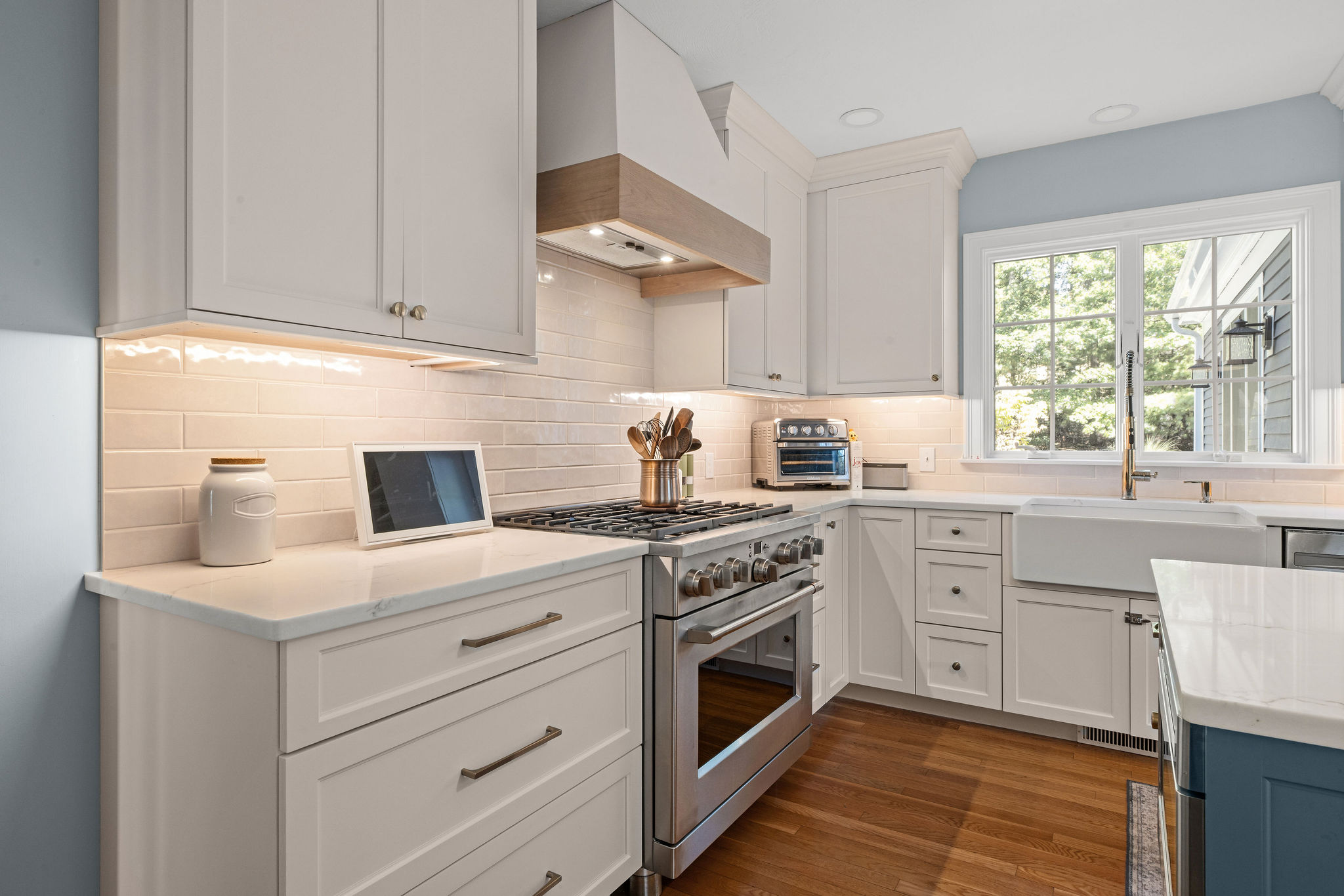 Gas range with a wood-trimmed hood and white subway tile in a Hanover kitchen remodel