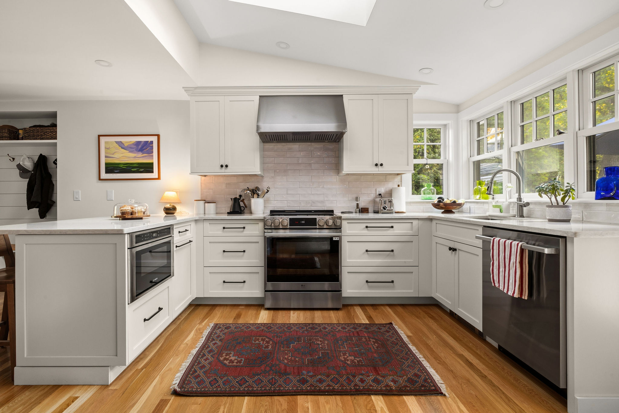 White kitchen remodel in Hingham with a vaulted ceiling, skylight, range, and quartz counters