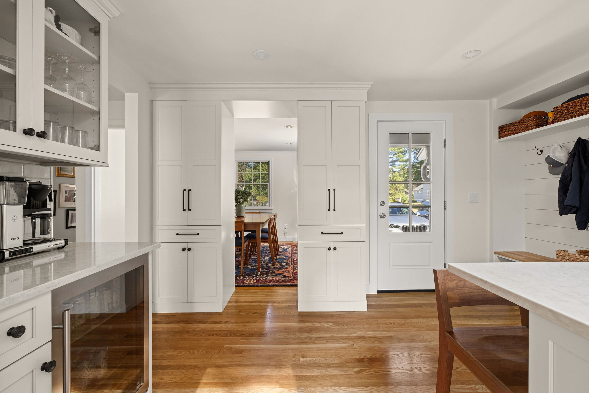 White cabinetry with quartz counters and an undermount sink under corner windows in a Hingham kitchen