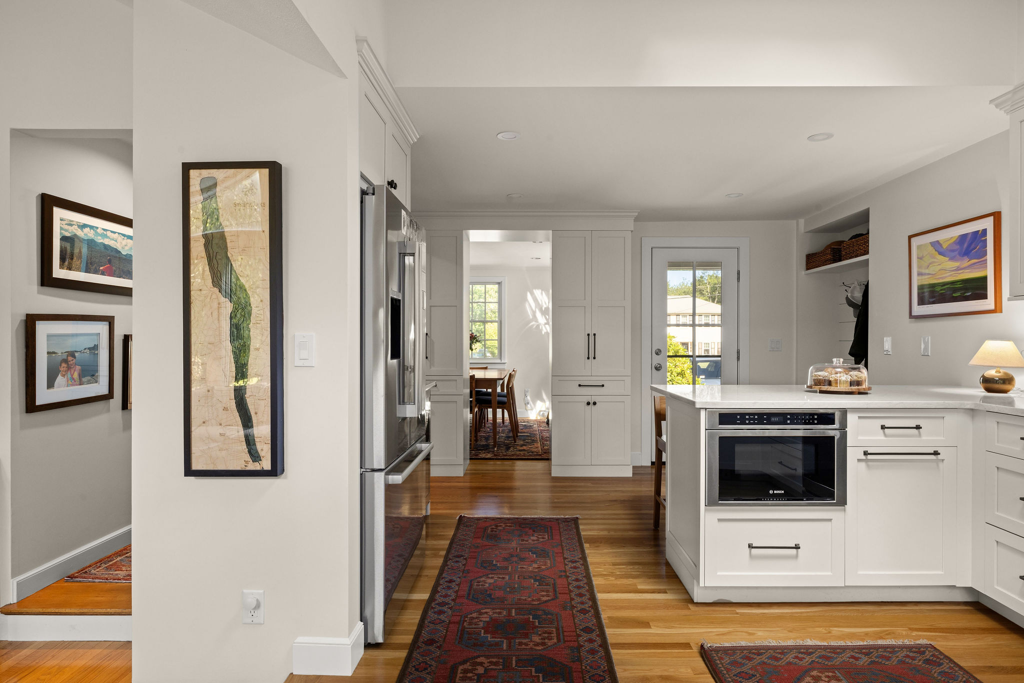 White Hingham kitchen with a peninsula, wall oven, and door to the dining room