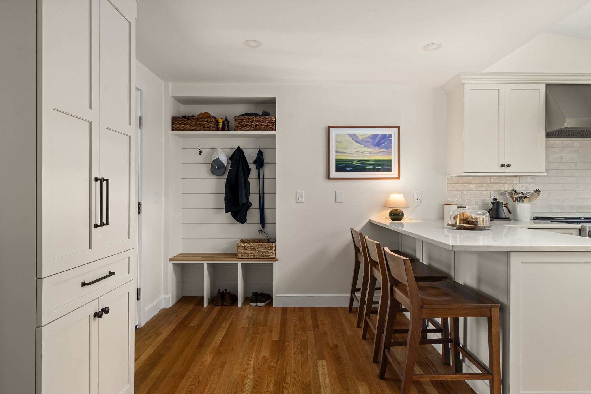 Built-in drop zone with a shiplap bench and breakfast bar in a white Hingham kitchen