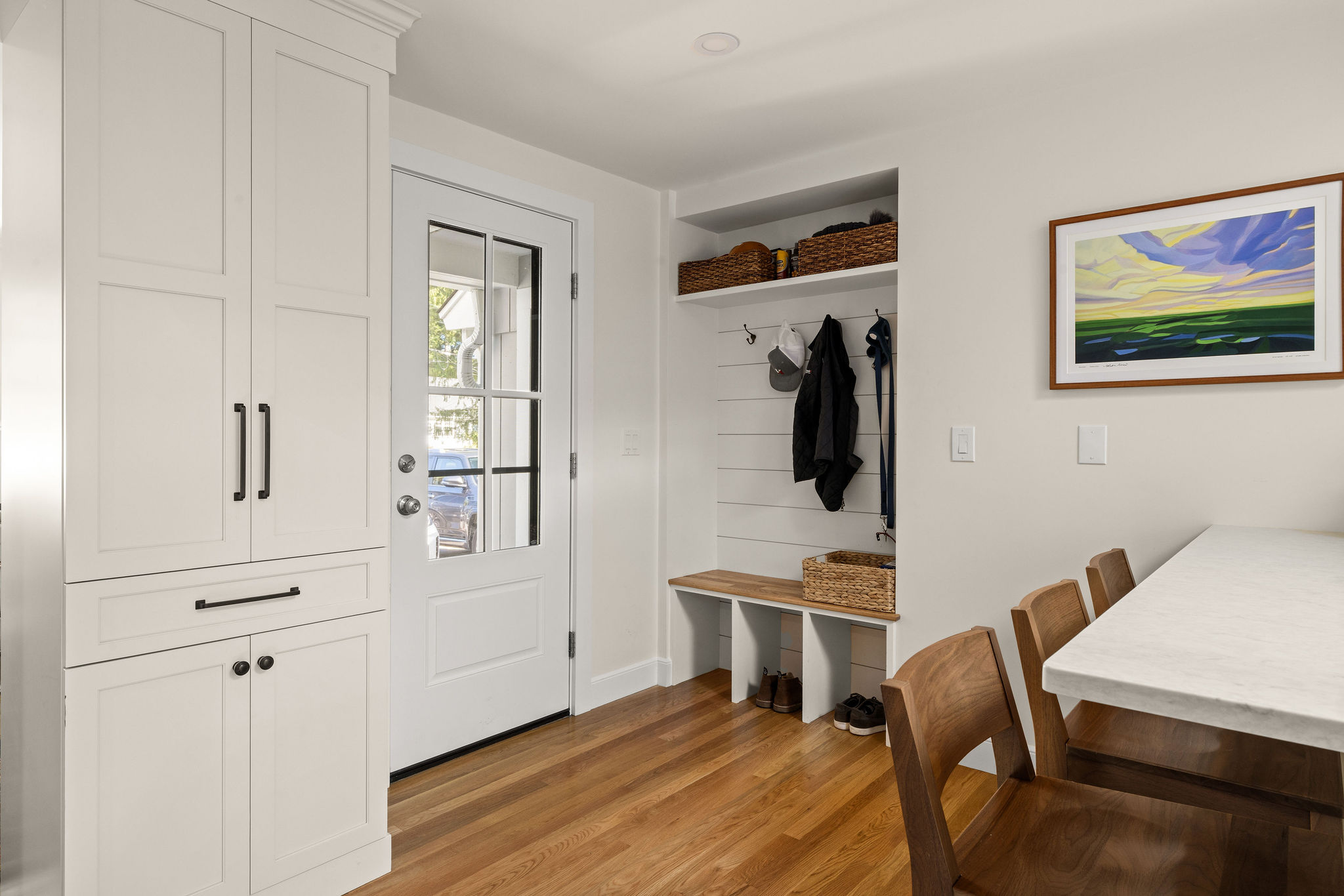 Mudroom drop zone with a shiplap bench, hooks, and a glass-panel exterior door in a Hingham kitchen