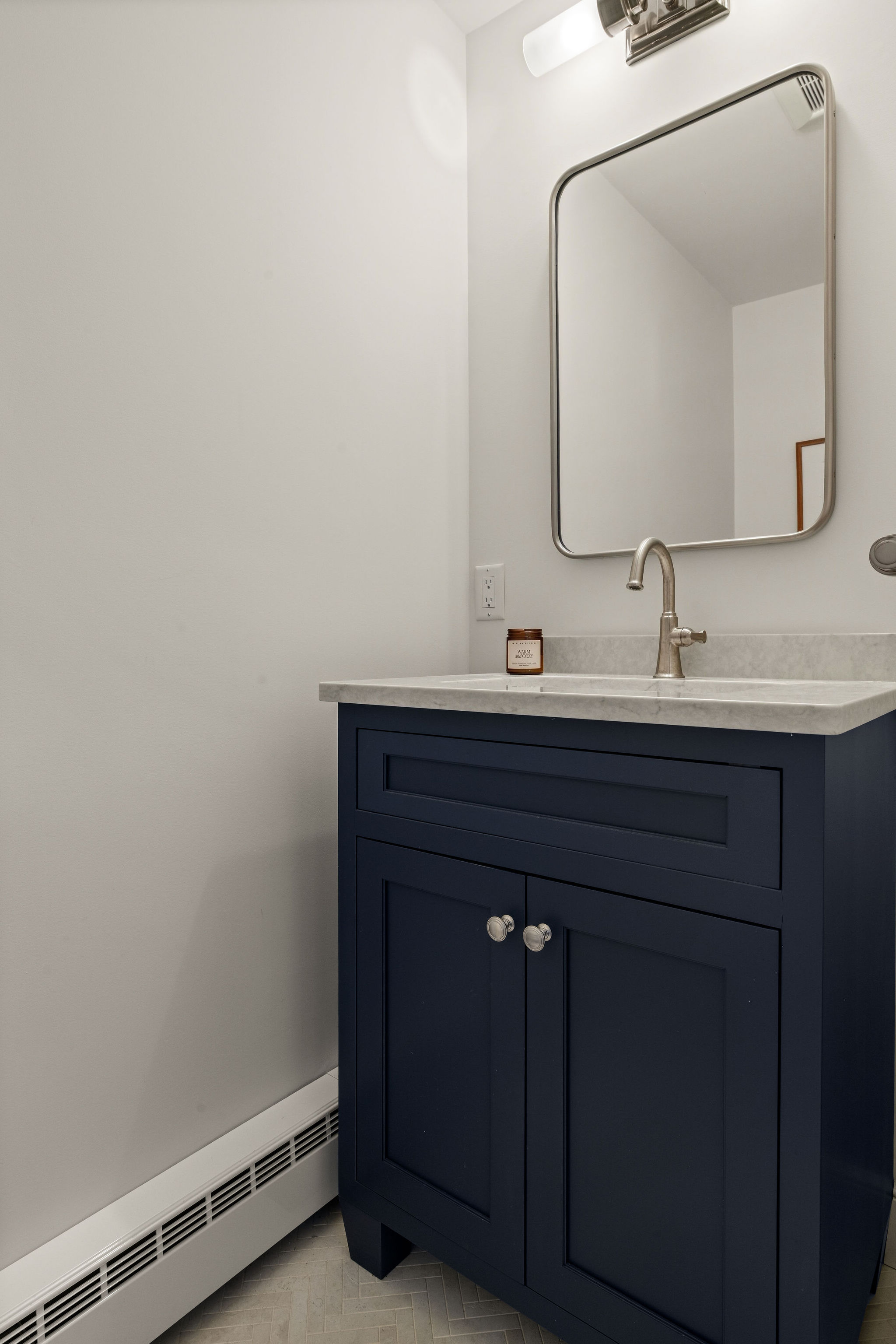 Navy powder room vanity with a quartz top and brushed nickel faucet in a Hingham remodel