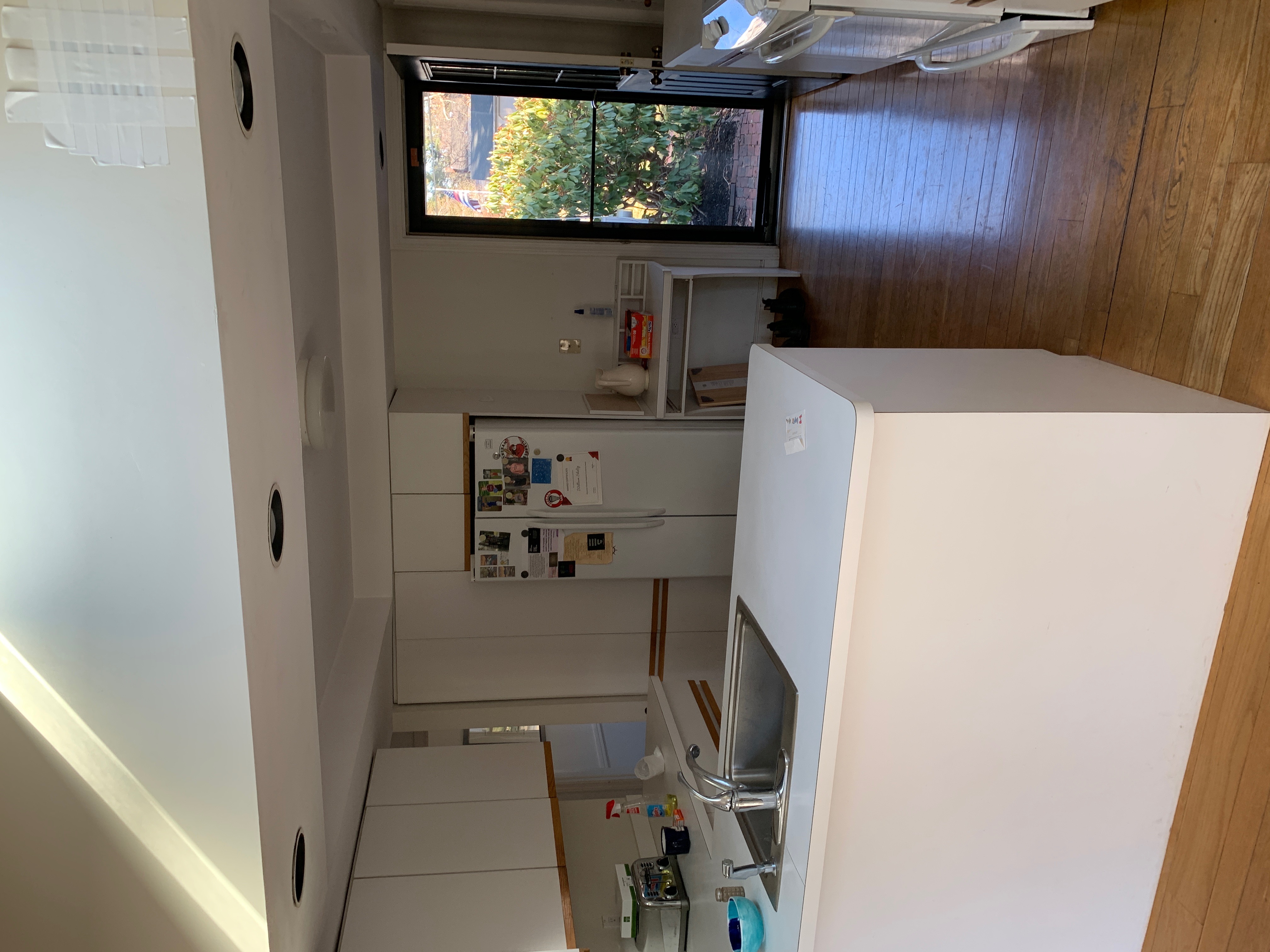 Before renovation: the original Hingham kitchen with white laminate cabinets, a peninsula sink, and dated appliances