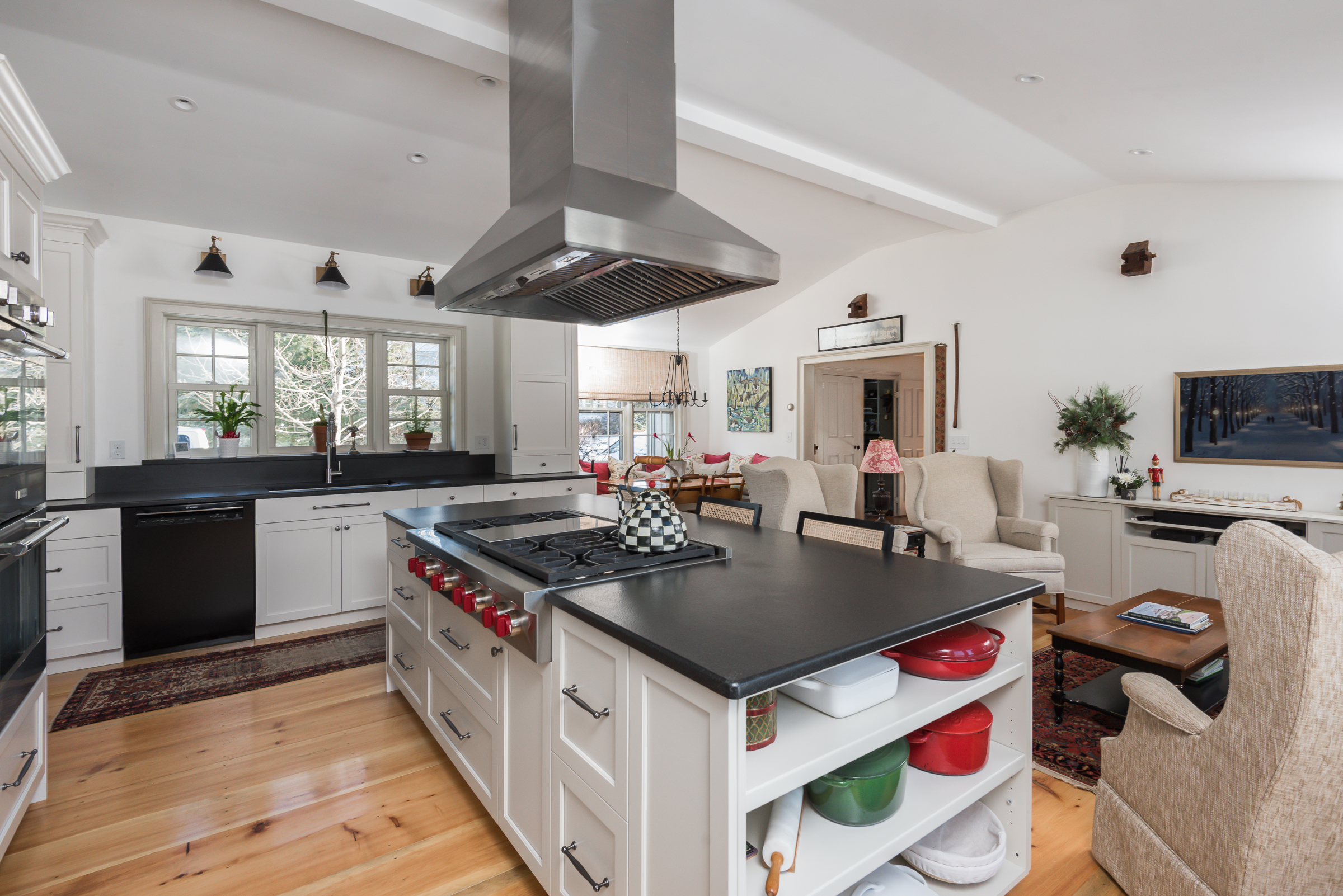 Island cooktop under a stainless hood, with open shelving facing the family room in a Duxbury kitchen