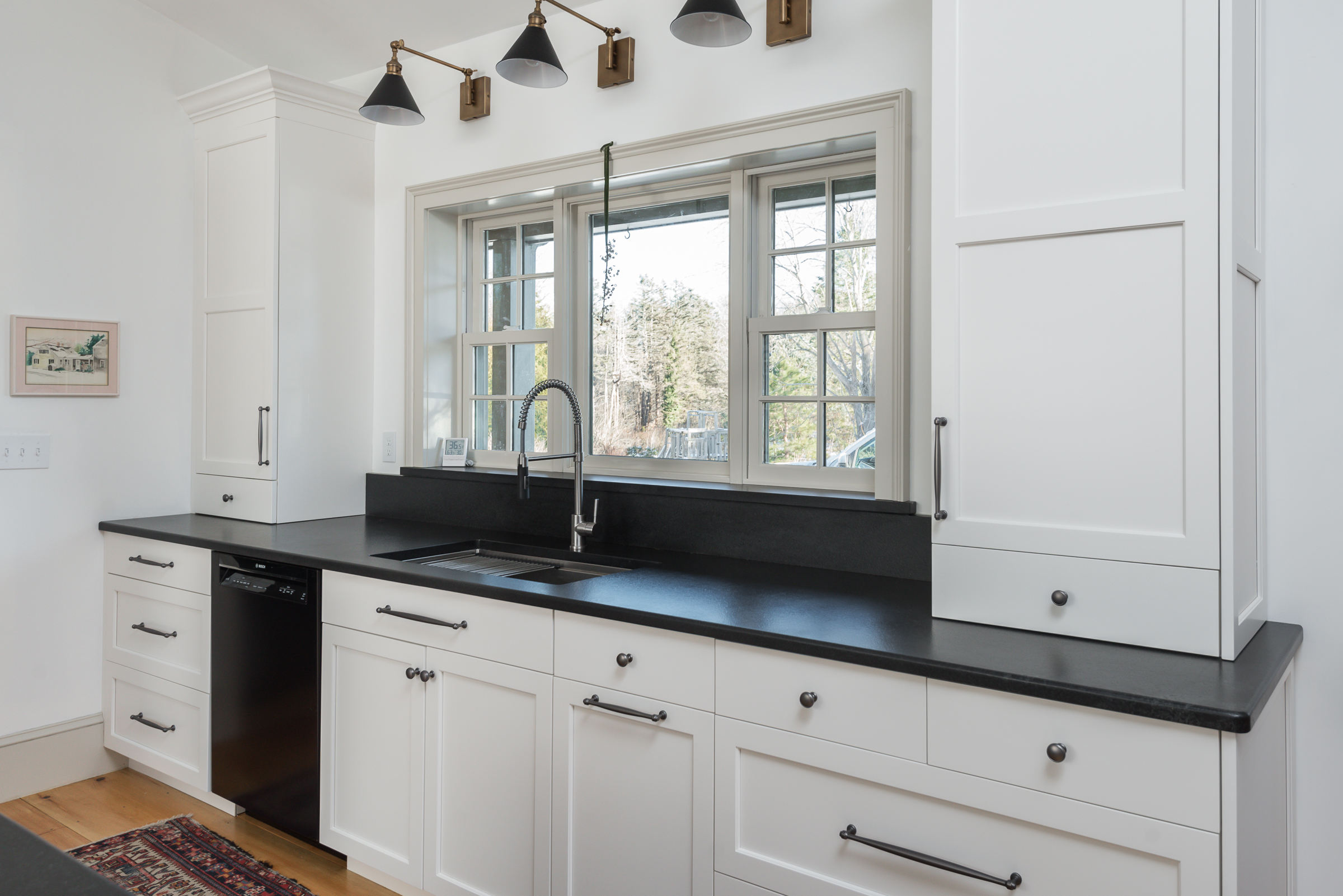 Triple window with divided lites over the relocated sink and black stone counters