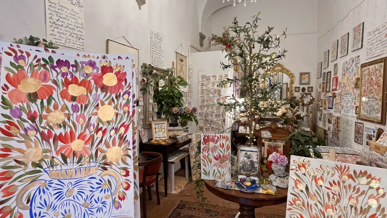 Interior of Serena Bifolchi's Siena shop on Via San Pietro — paintings, antique furniture, and jars of natural pigments