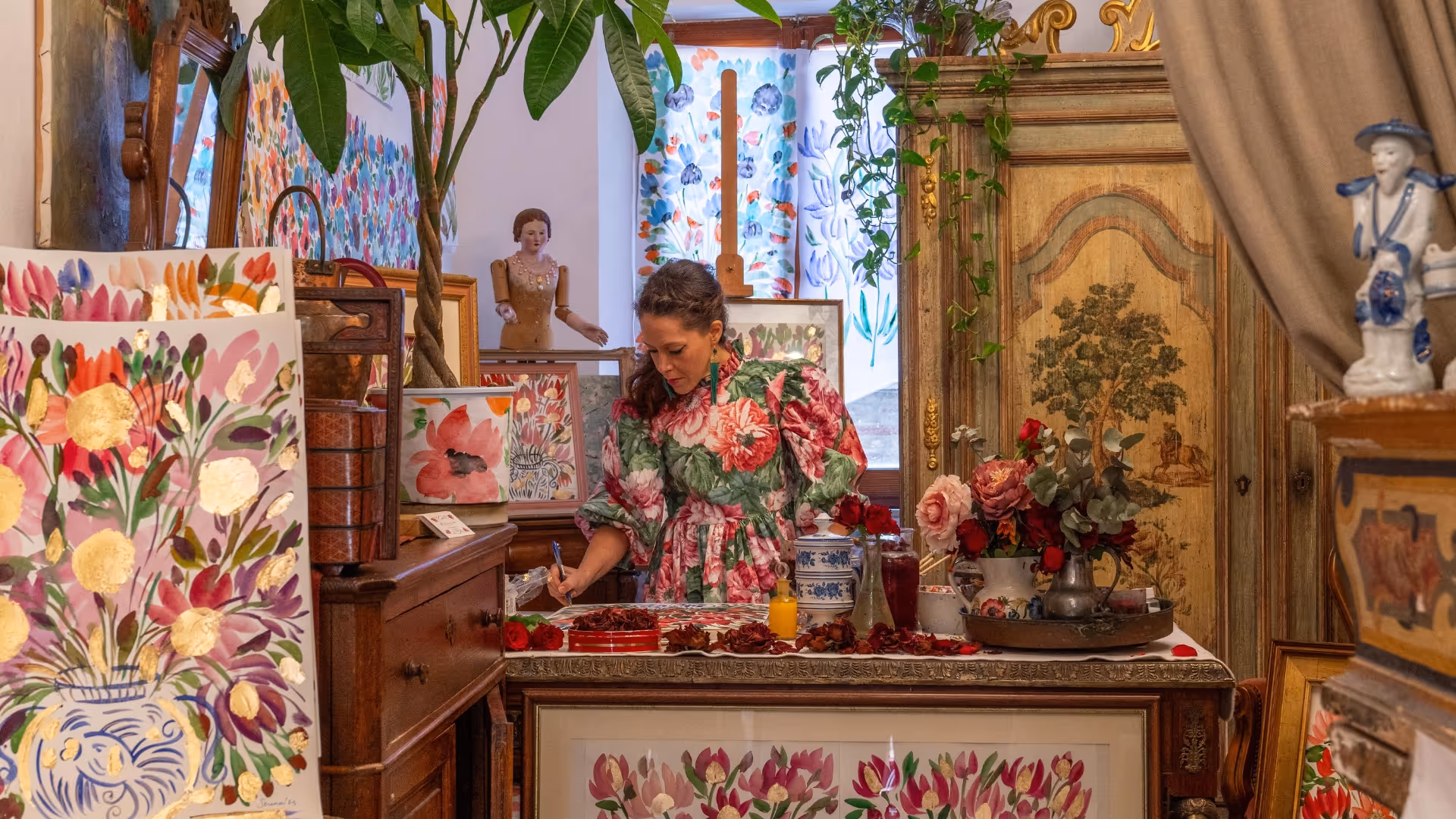 Serena Bifolchi painting in her studio in Tuscany, surrounded by floral artworks and antique furniture.