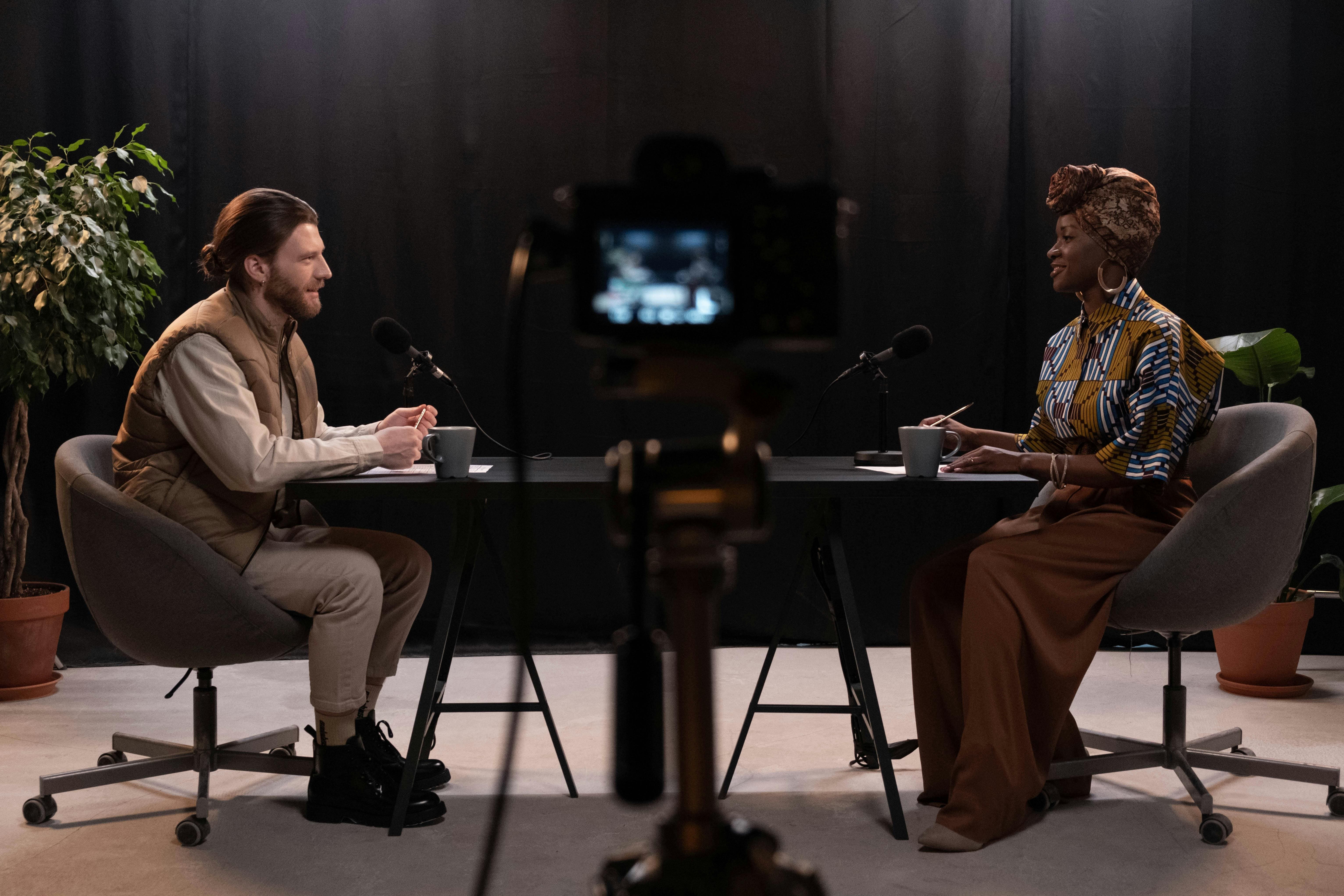 Image of a black woman being interviewed by a long hair white man.