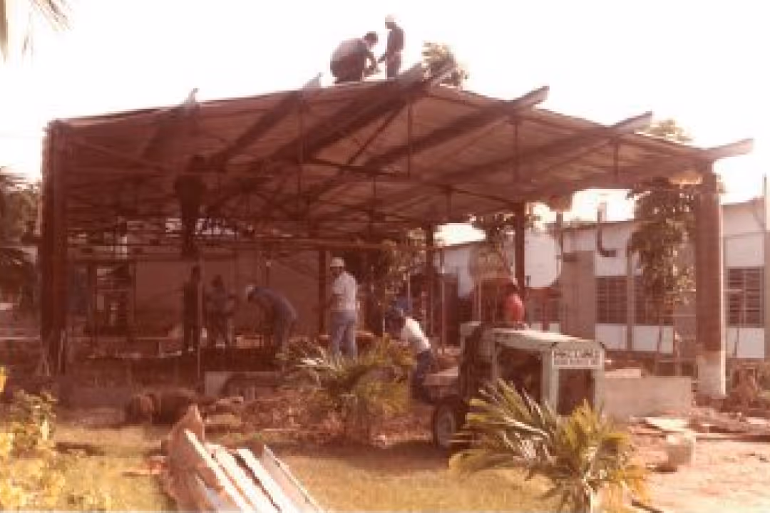 Construction workers assembling a metal roof structure on an outdoor site during daytime.