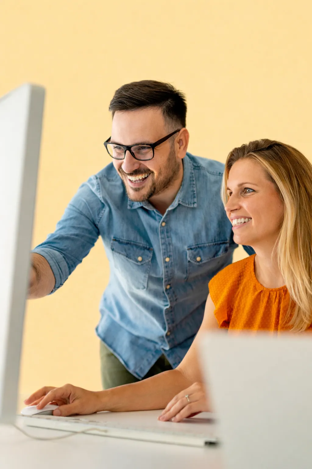 Two colleagues leaning in to look at a monitor
