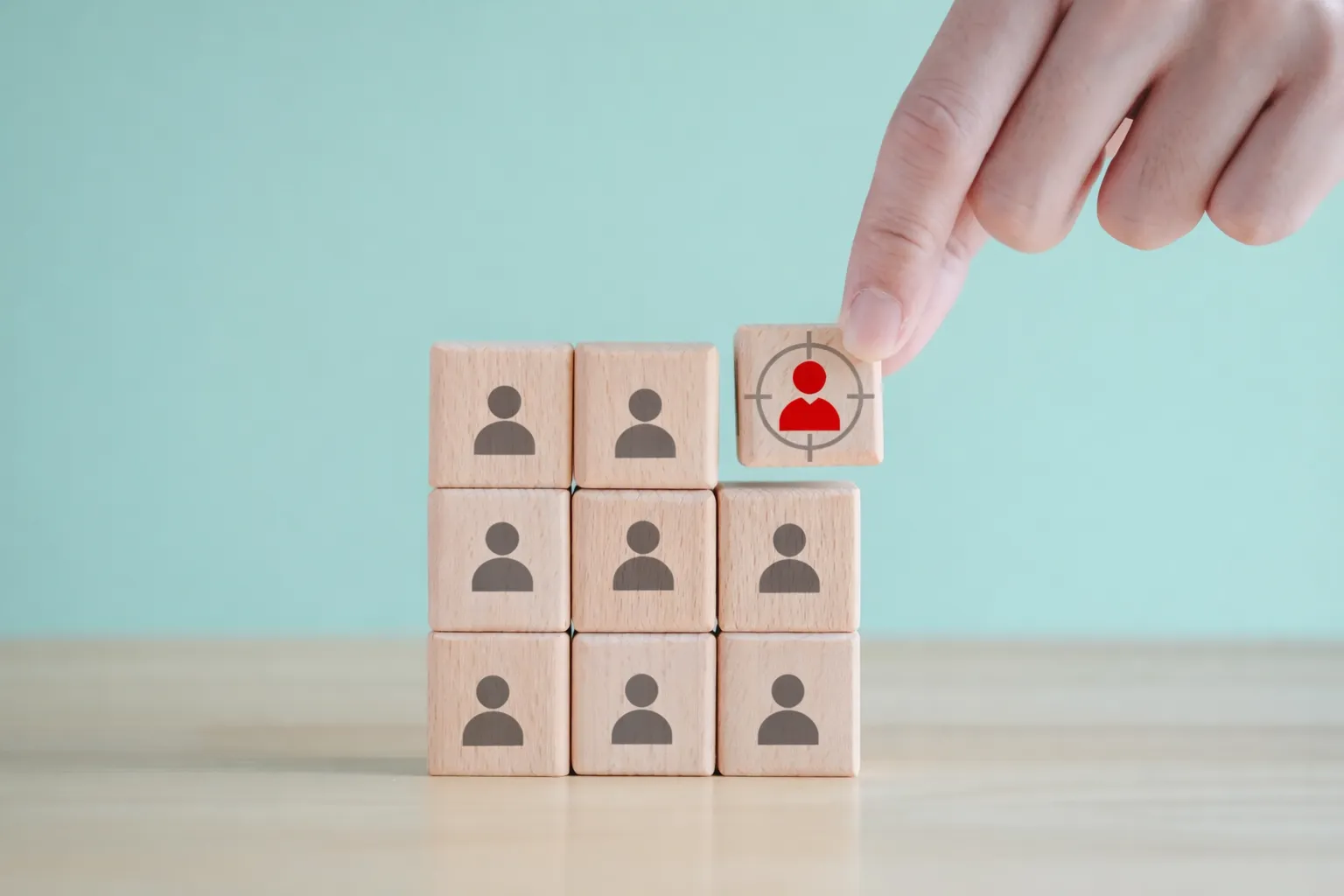 Hand placing a highlighted block in a grid of person-icon blocks