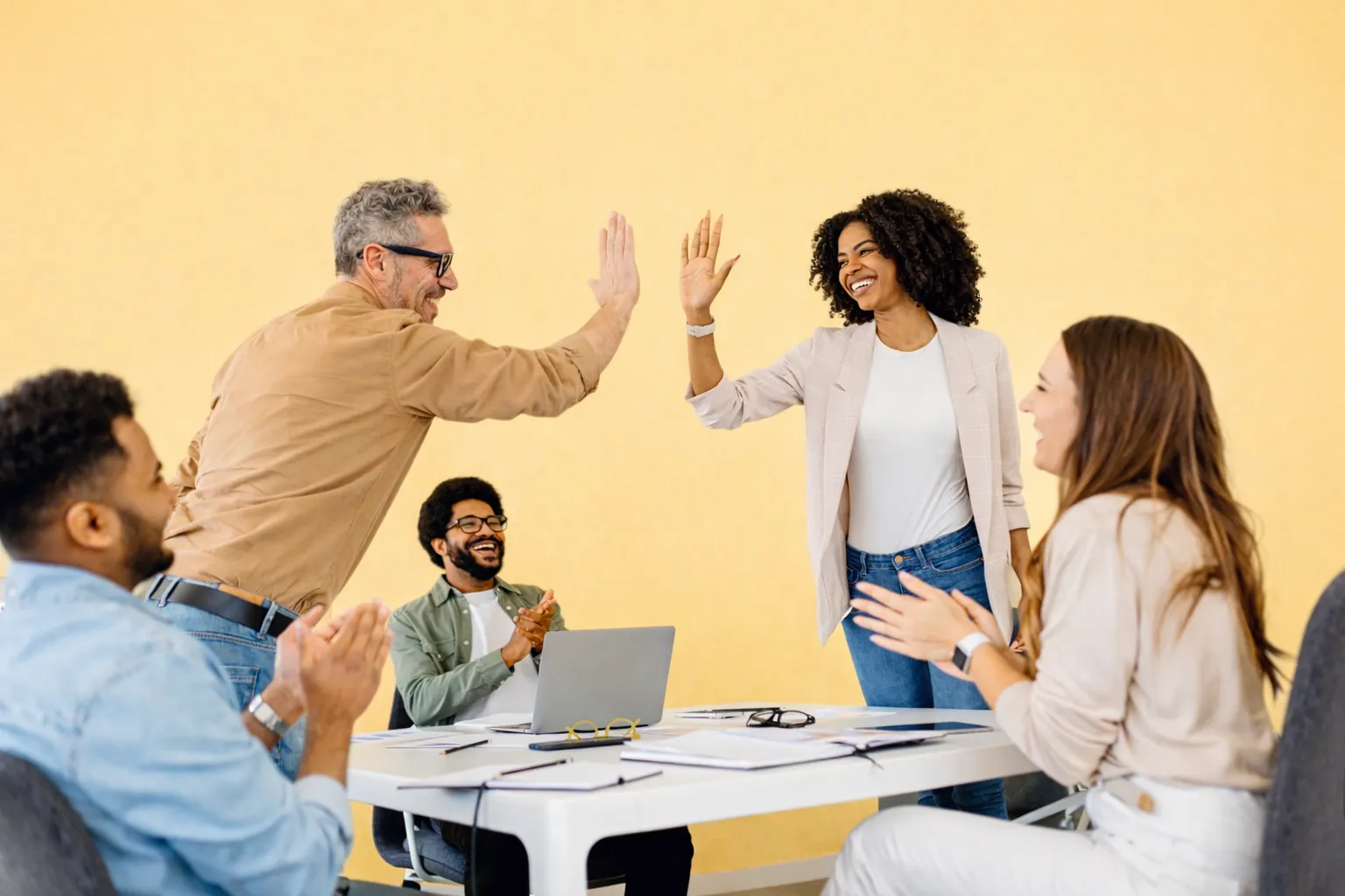Team high-fiving around a meeting table