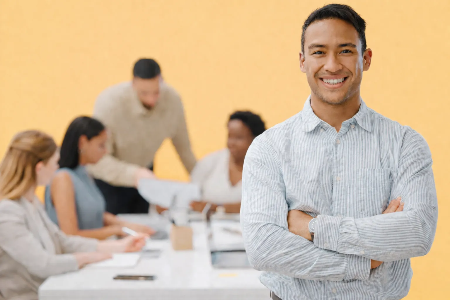 Smiling man in the foreground of a team meeting
