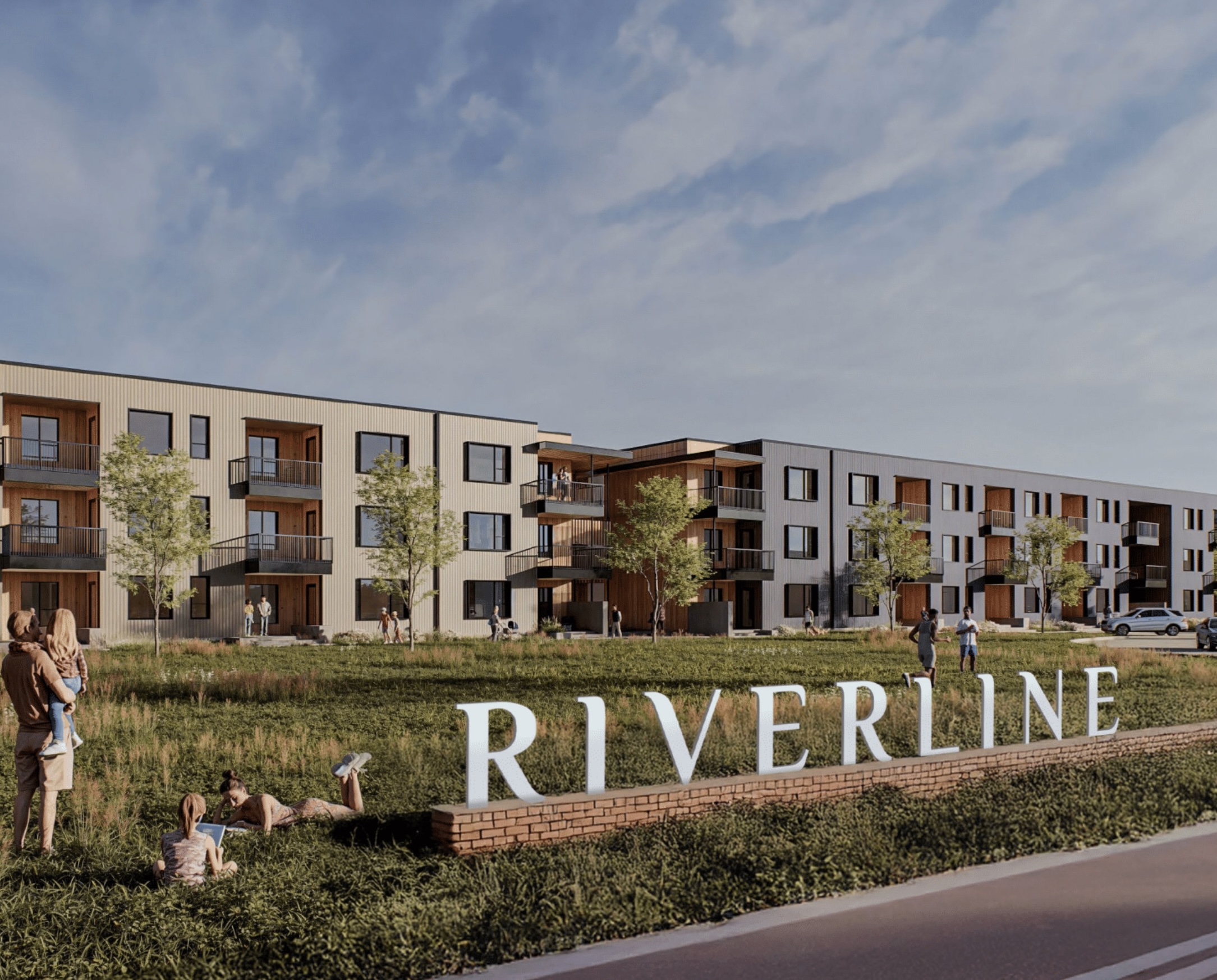 Modern three-story apartment buildings with balconies behind a grassy lawn and large RIVERLINE sign.