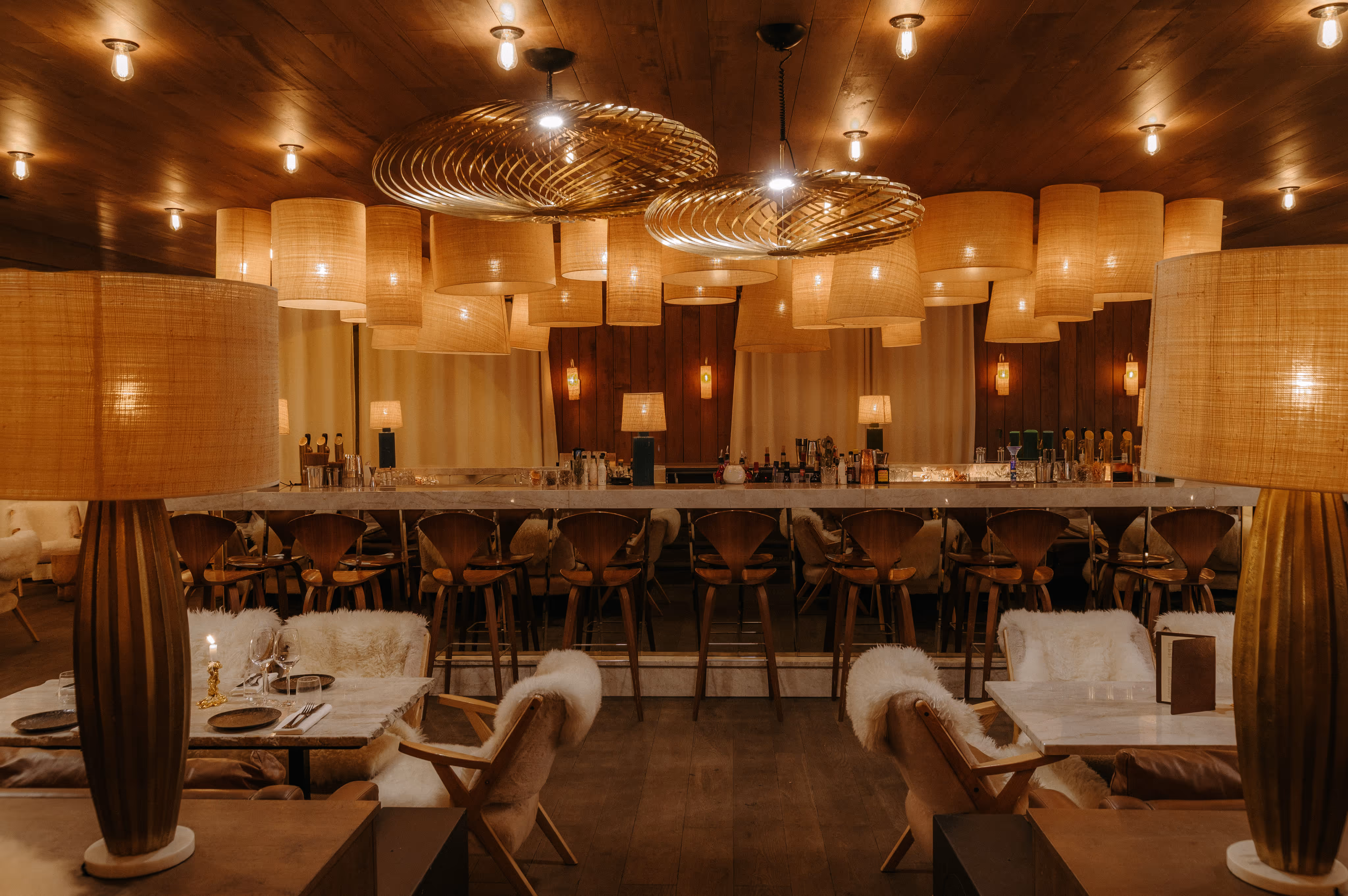 Overview of the room at the ChaCha restaurant, an address by the Annie Famose Group (AFGroupe), showcasing its suspended light fixtures and stylish bar.