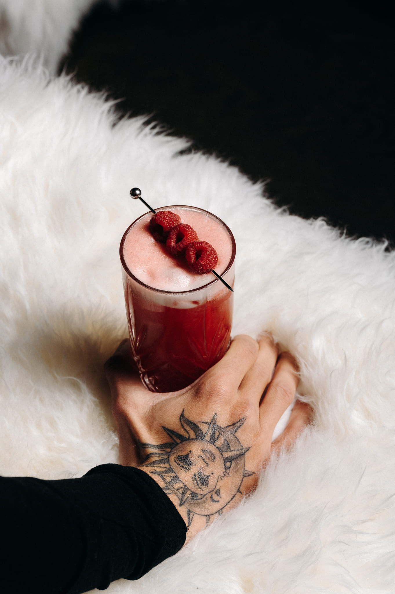Close-up of a raspberry cocktail, held by a tattooed hand, at ChaCha restaurant in Megève, Annie Famose group (AFGroupe).
