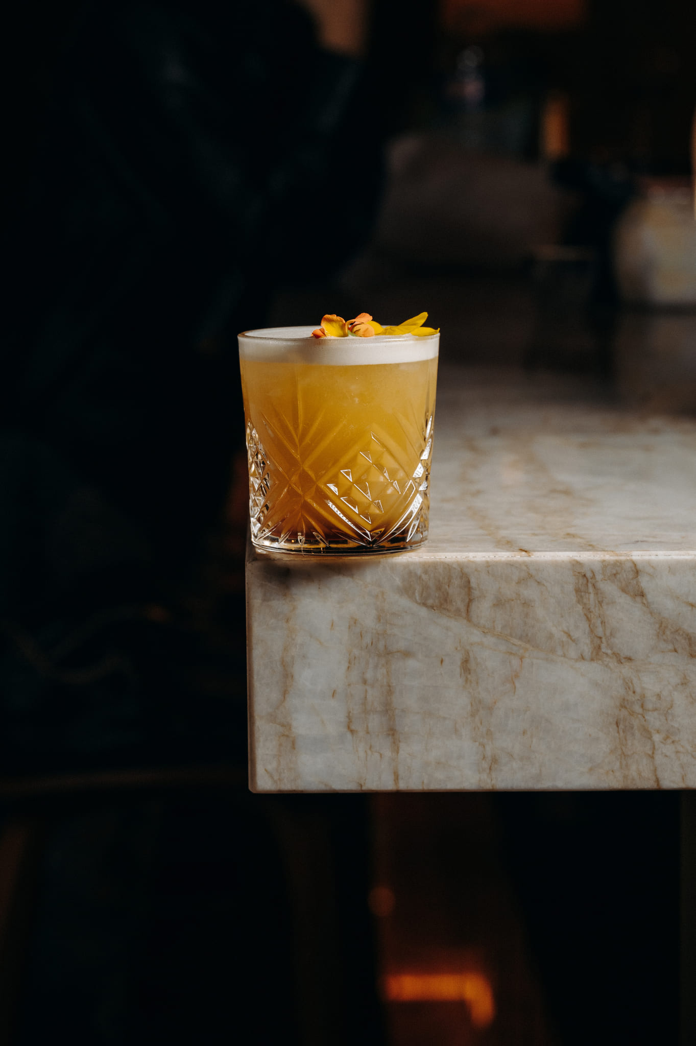 A flower-garnished cocktail on a marble table at the ChaCha restaurant in Megève, Annie Famose Group (AFGroupe).