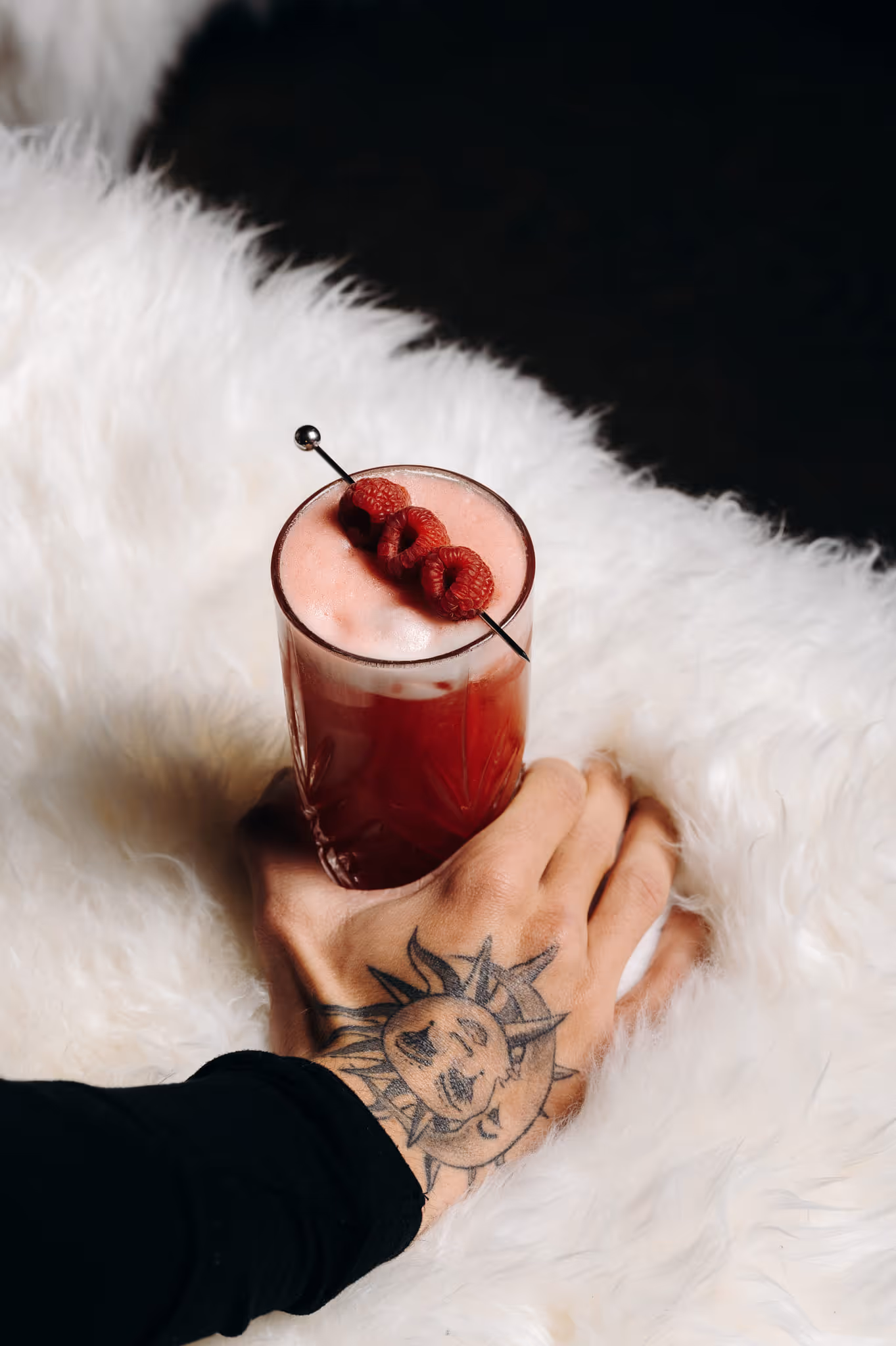 Close-up of a raspberry cocktail, held by a tattooed hand, at the ChaCha restaurant in Courchevel, Annie Famose group (AFGroupe).