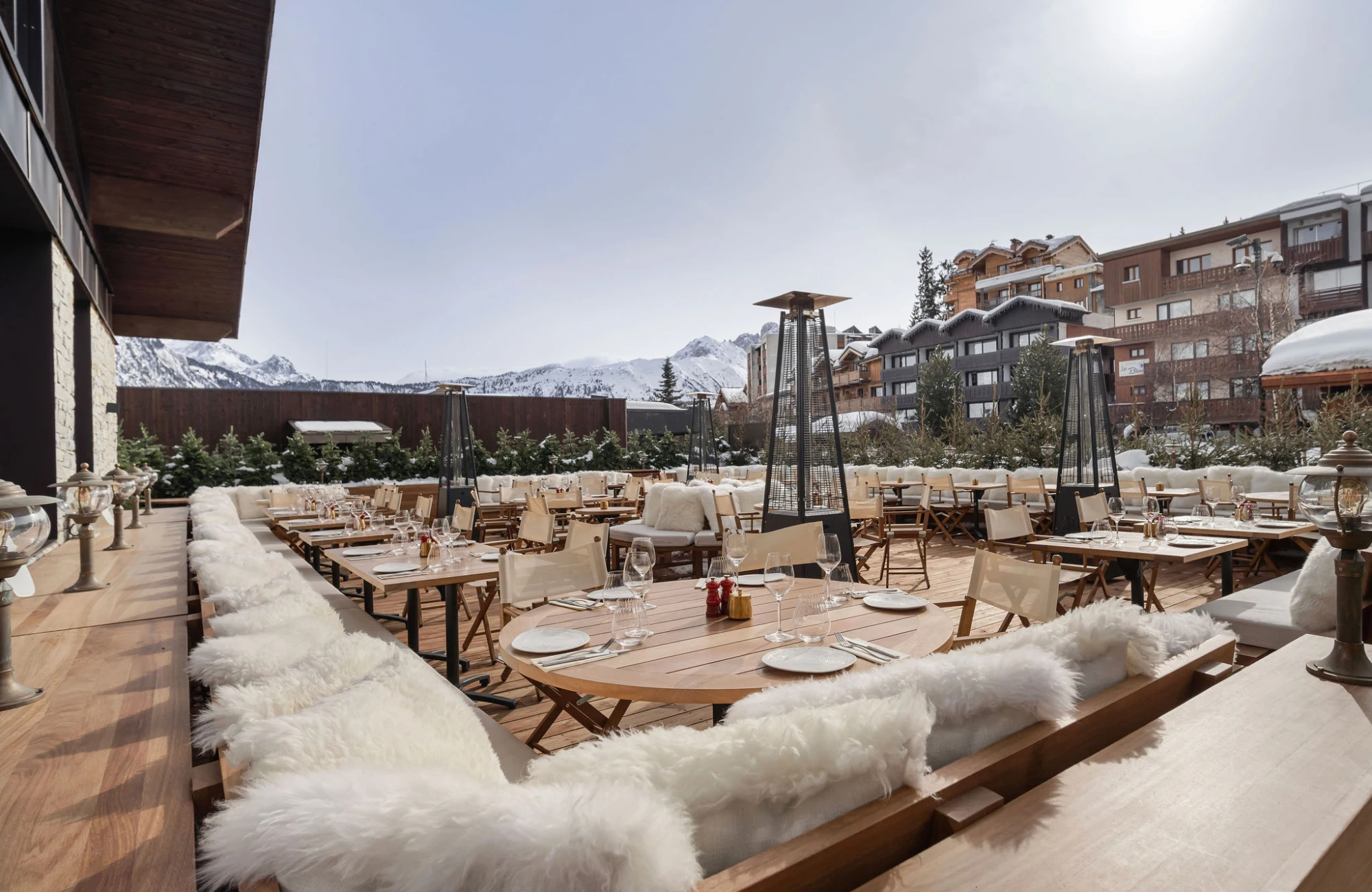 Sunny terrace at Courchevel's ChaCha restaurant, part of the Annie Famose group (AFGroupe), featuring comfortable fur seating facing the peaks.