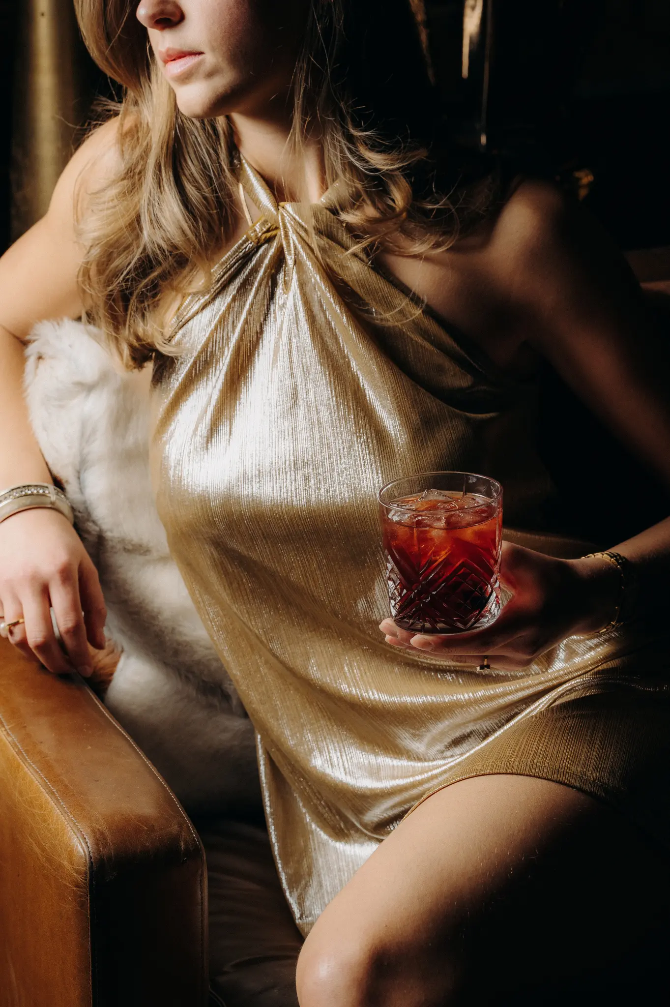 A person in an elegant dress holding a cocktail in a plush atmosphere at the ChaCha restaurant, Megève, Annie Famose Group (AFGroupe)