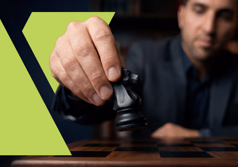 Man in dark clothing holding and moving a black knight chess piece over a chessboard.