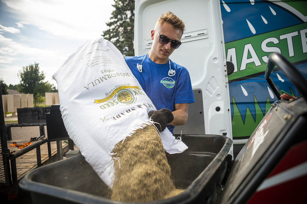 lawn team prepping grass seed to be applied