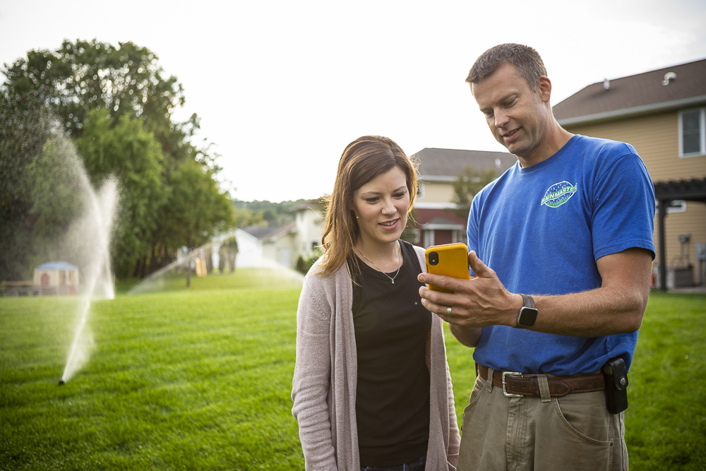 irrigation technician and customer look at app for sprinklers