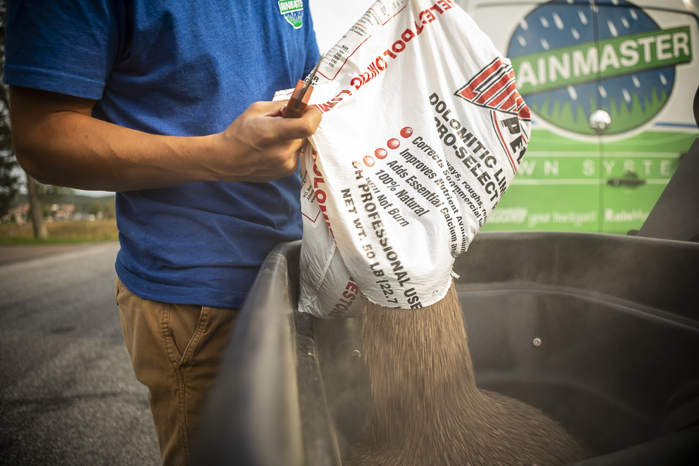 lawn care team pours lime into spreader