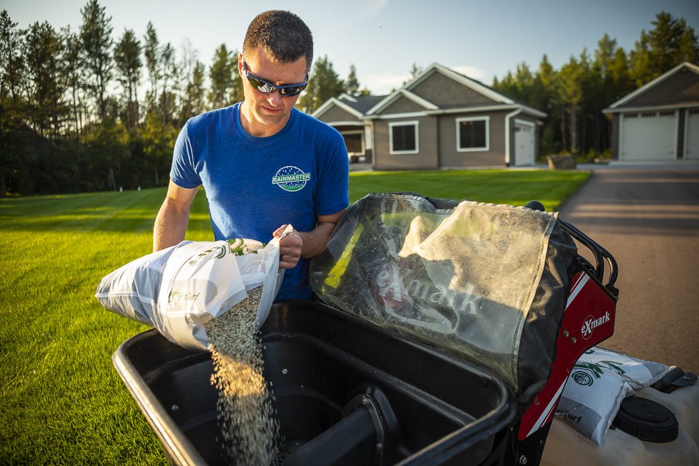 Lawn care professional applying fertilizer to make lawn thicker