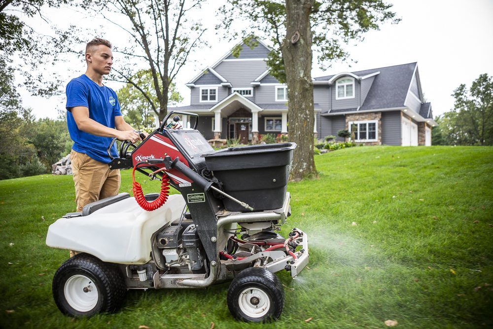 lawn care expert spreads liquid grub control