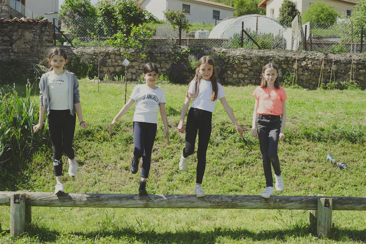 4 filles en équilibre sur la  poutre dans le petit pré.