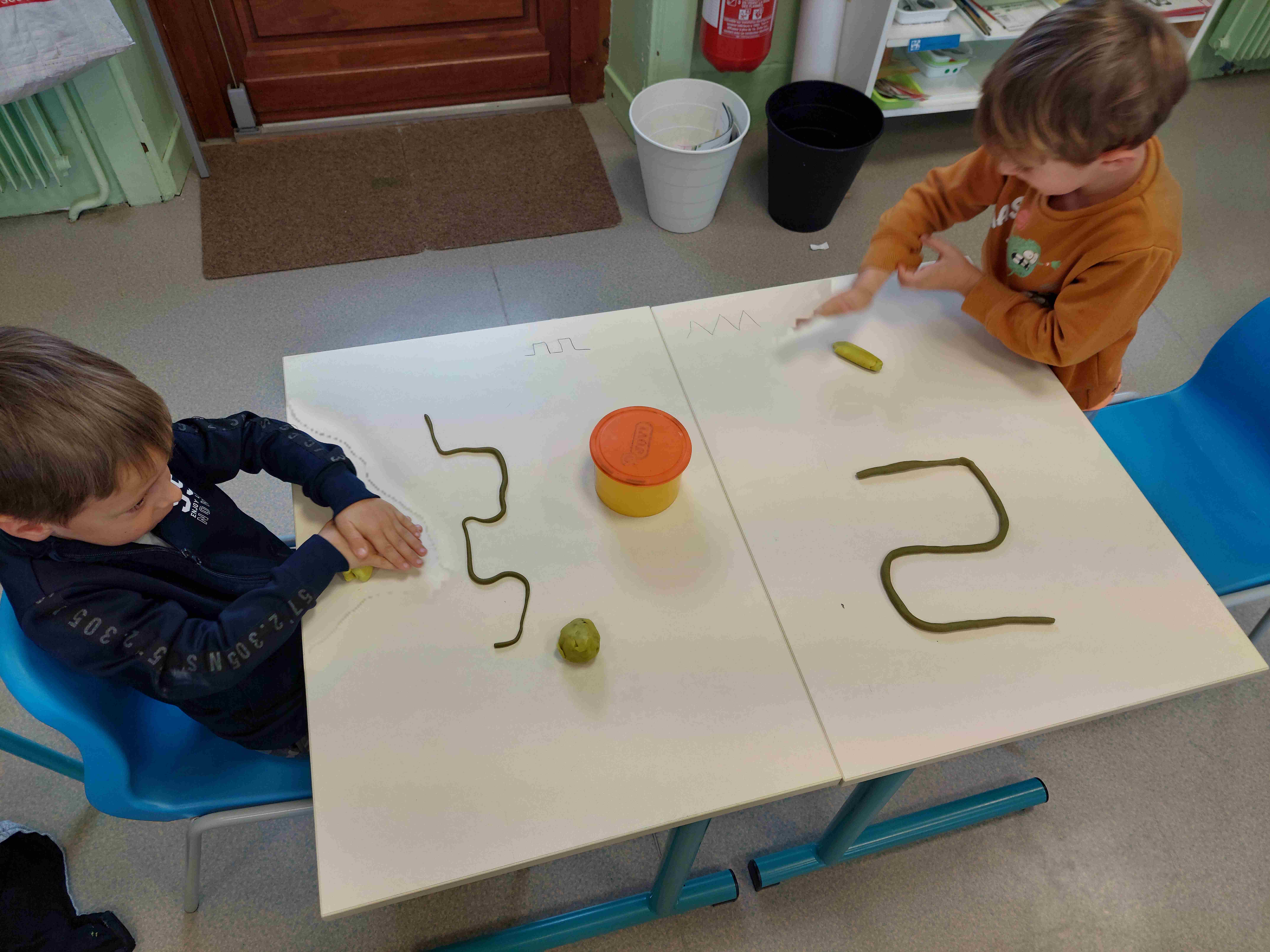 2 enfants faisant de la pate à modeler à leur bureau