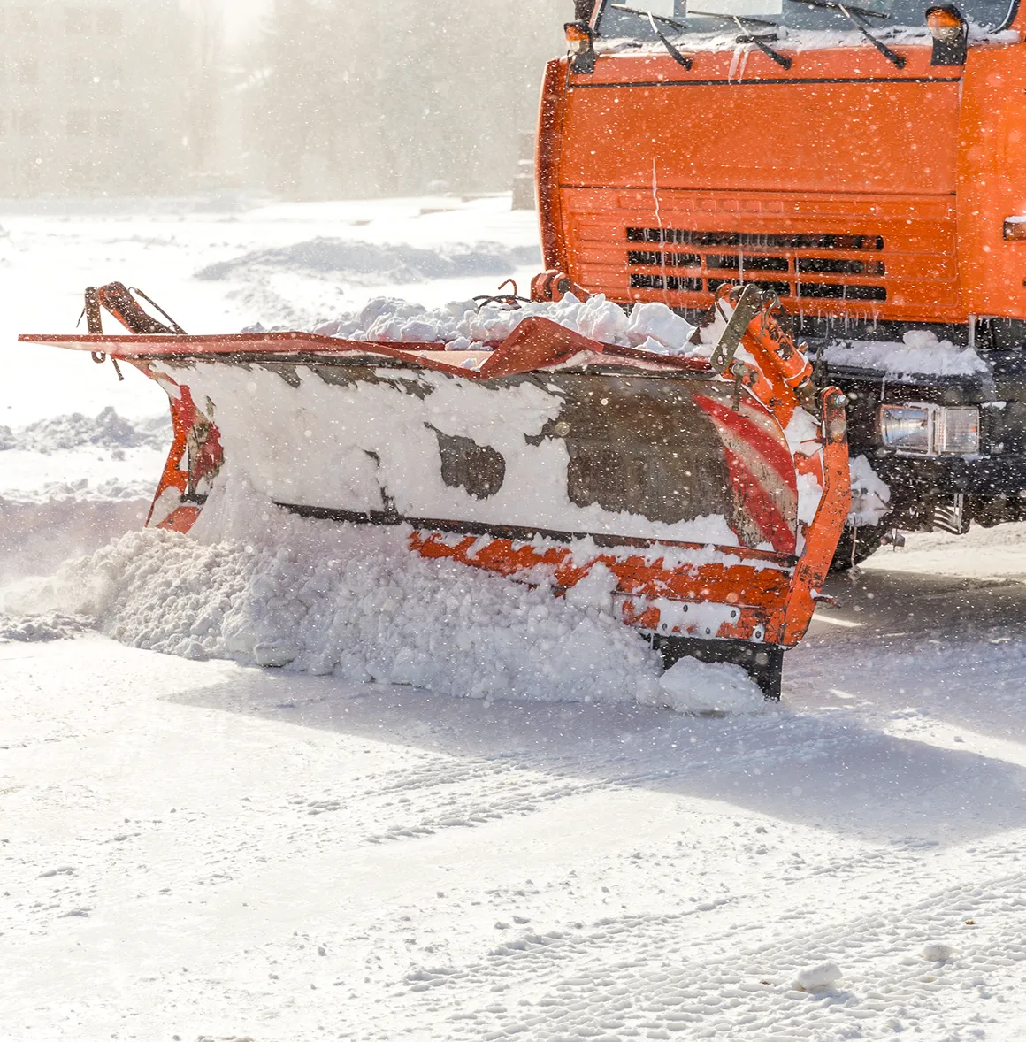 Oranger Schneepflugfahrzeug entfernt Schnee während Schneefall.