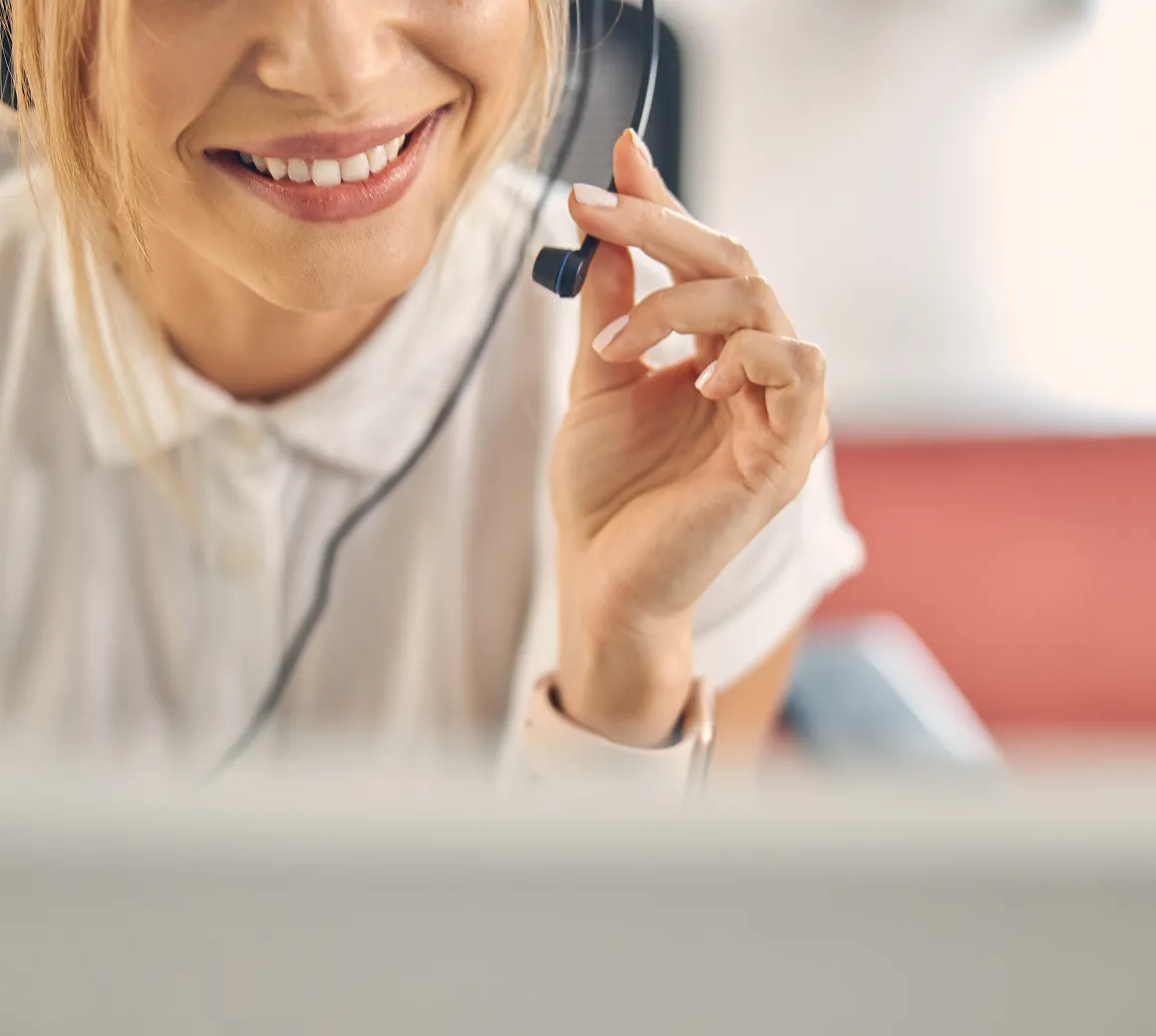 Lächelnde Frau mit Headset, die mit Kundenbetreuung oder Support hilft.