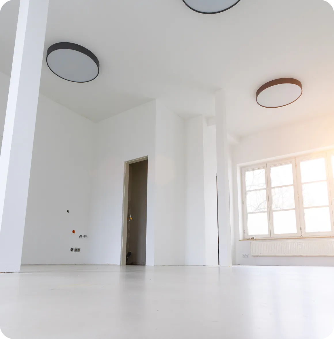 Modernes dreistöckiges Wohngebäude mit weißen Wänden und Holzakzenten neben einem gepflegten Garten und gepflastertem Gehweg bei sonnigem Himmel.