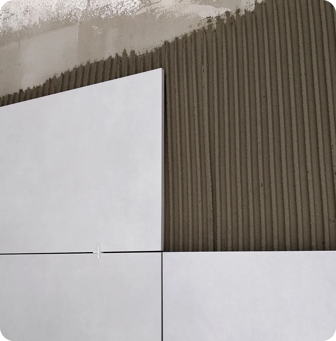 Zwei Männer in blauen Overalls heben gemeinsam ein schwarzes Ledersofa in einem hellen Raum mit Umzugskartons.