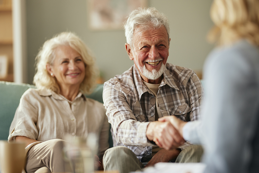 Seniors smiling shaking hands with a woman