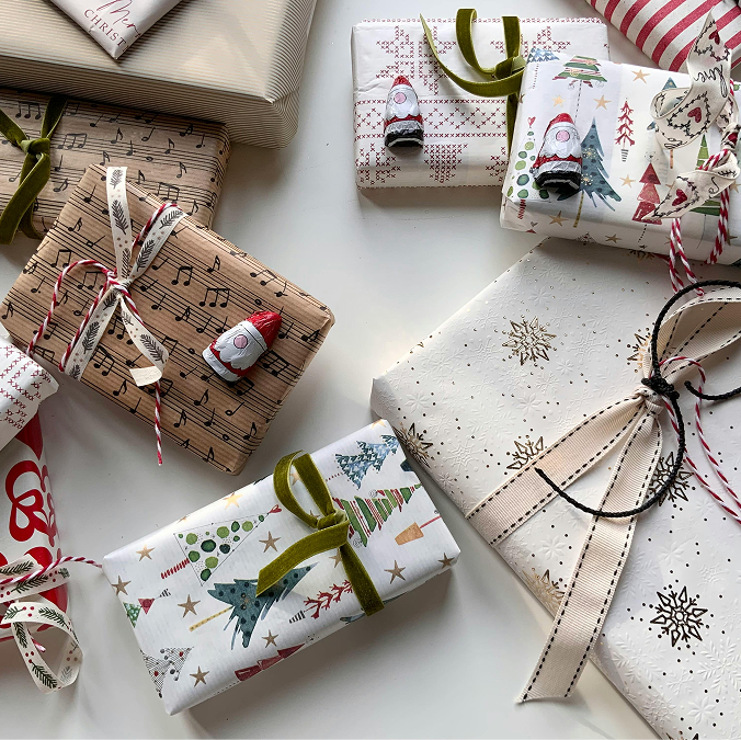A young woman in a black blazer smiling and leaning her head toward an elderly man in glasses and a checked shirt sitting beside her outdoors.