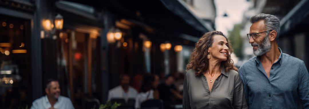 Smiling middle-aged couple walking together on a city street in the evening.
