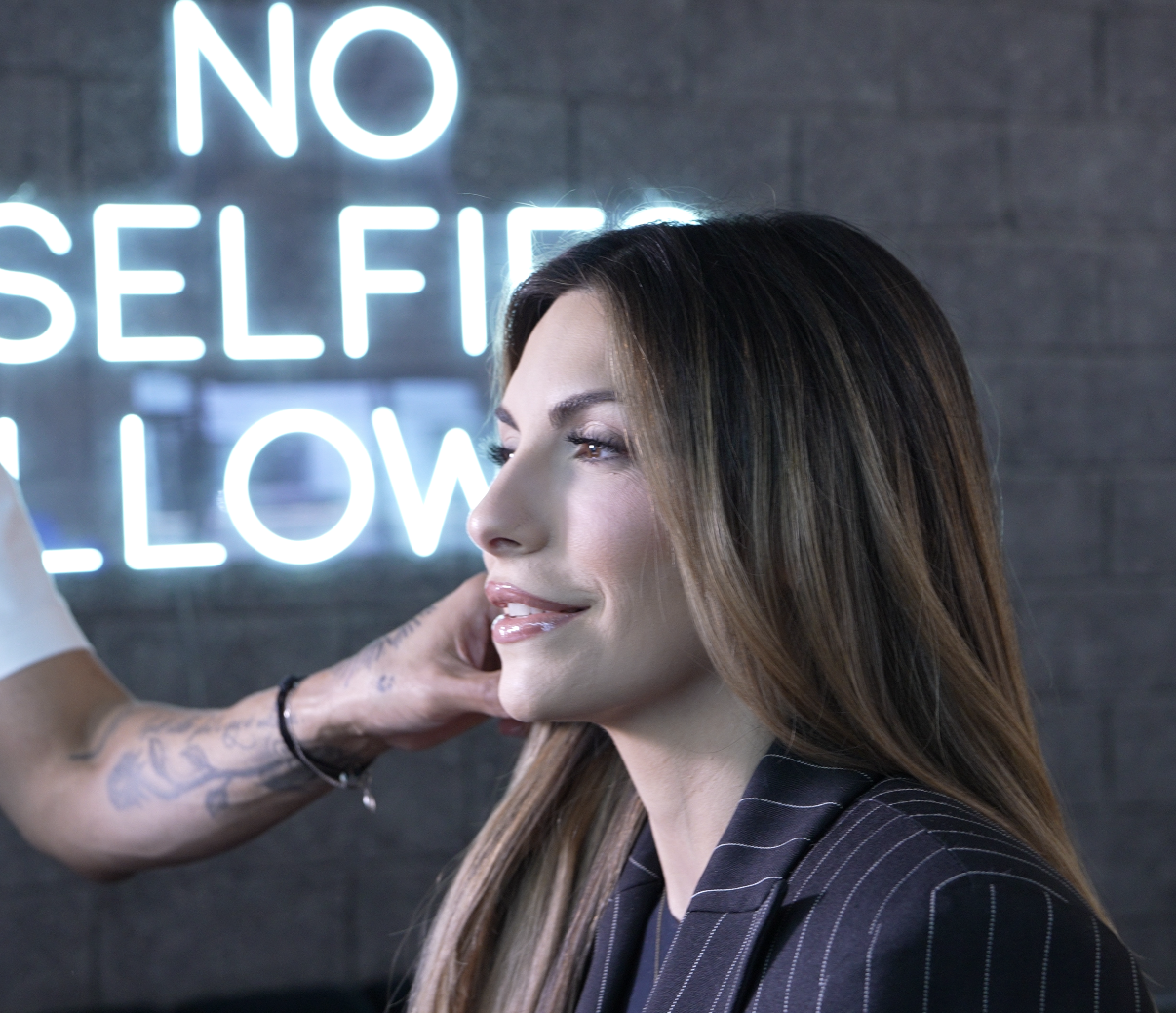 Hands with white nail polish holding a black smartphone displaying 'Jaclym ROMO authority through authenticity' on the screen.