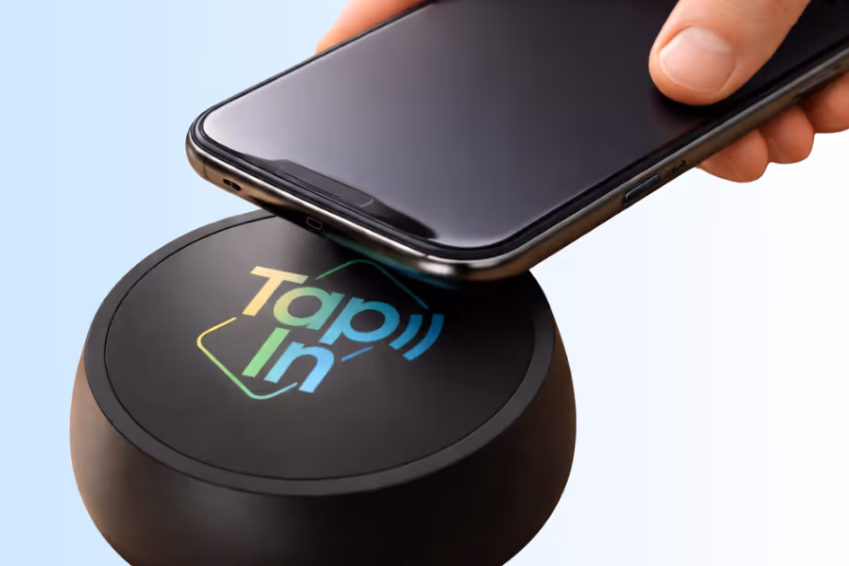 Hand holding a smartphone above a black device with 'TapIn' logo for contactless interaction.