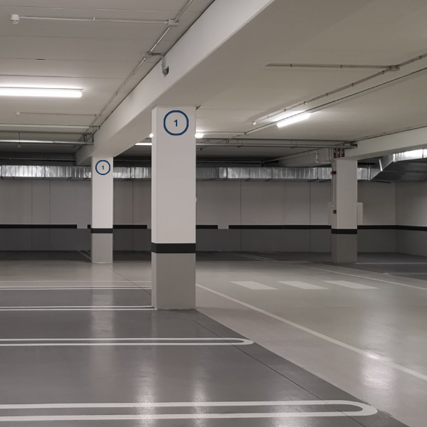 Empty indoor parking garage with numbered white pillars and marked parking spaces.