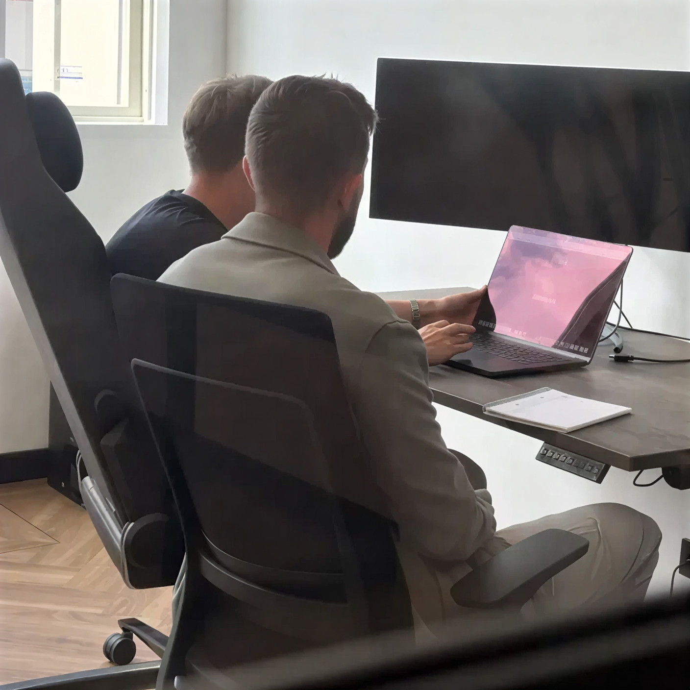 Human hand reaching out to touch a robot hand against a neutral gray background.