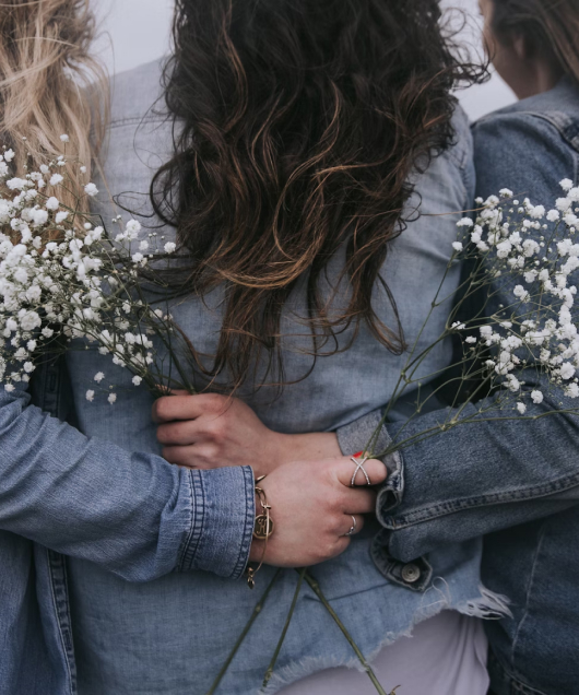 Group of women from the back. hugging and holding flowers