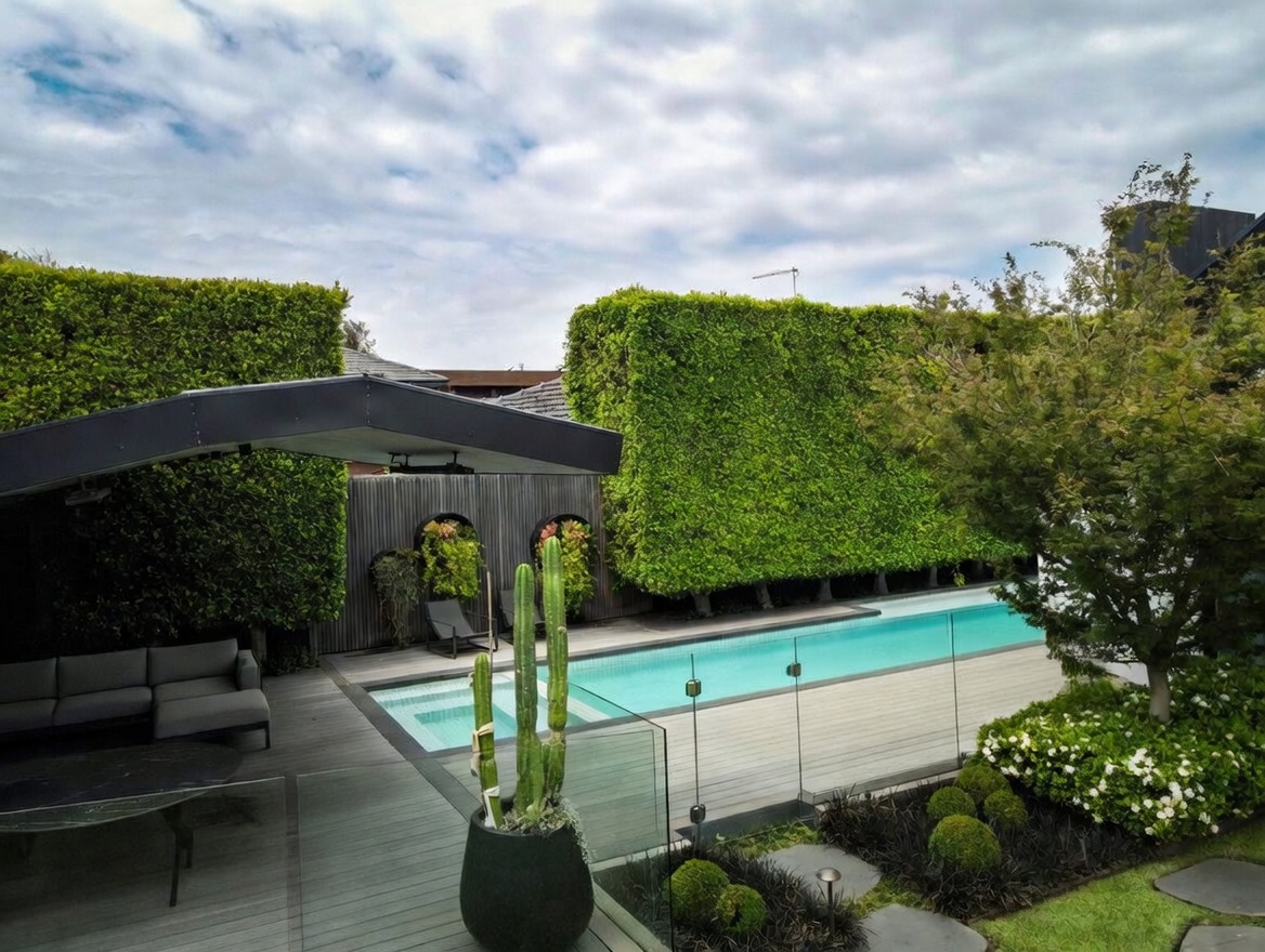 Manicured formal garden with lush green hedges, swimming pool and modern outdoor entertaining area in Brighton